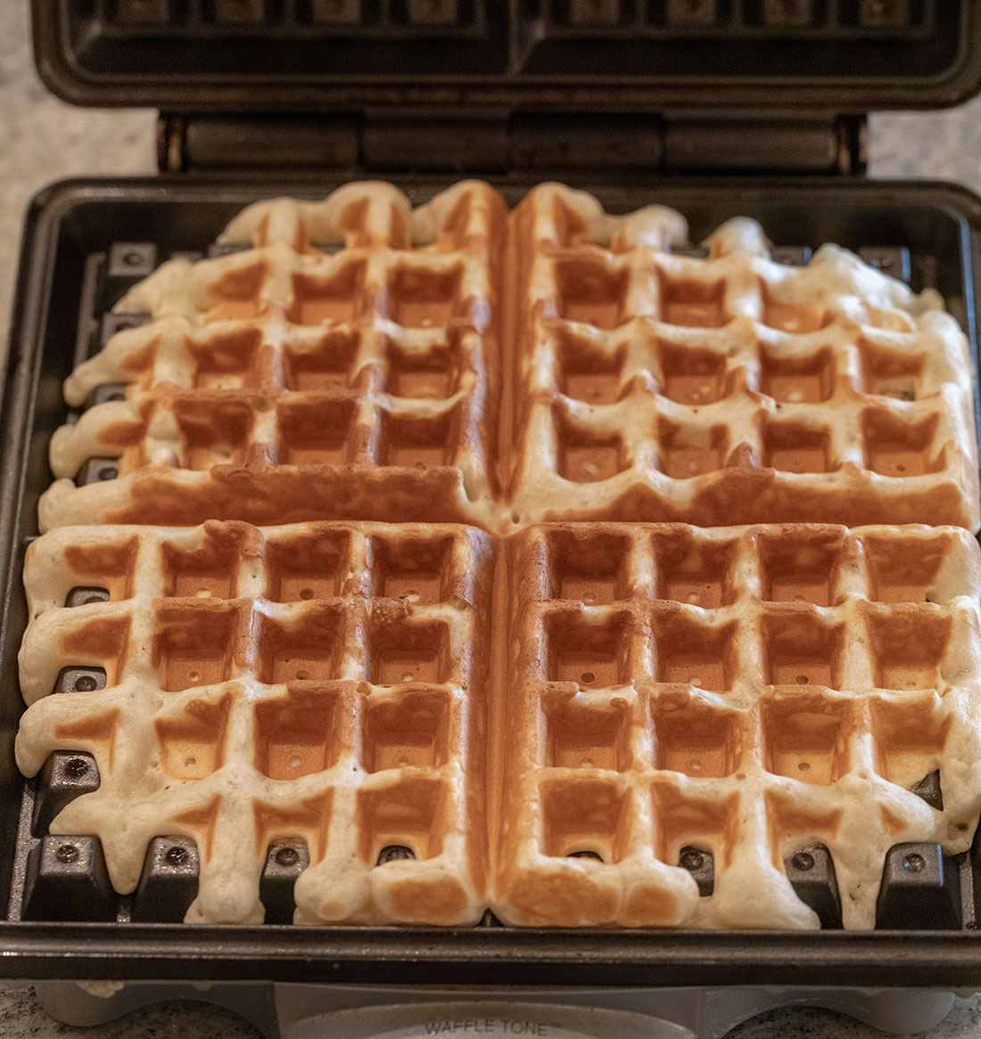 Waffles cooked golden brown in an open waffle maker.