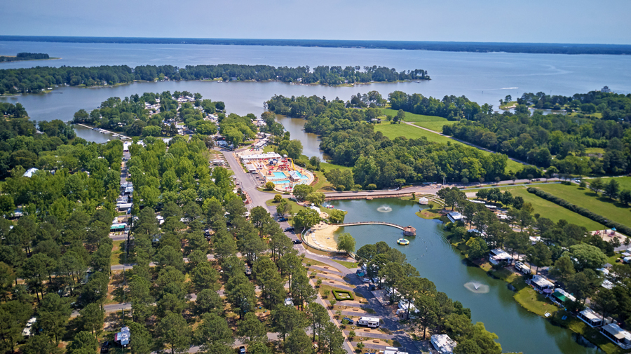 An aerial view of a riverside RV resort with a canal running through.