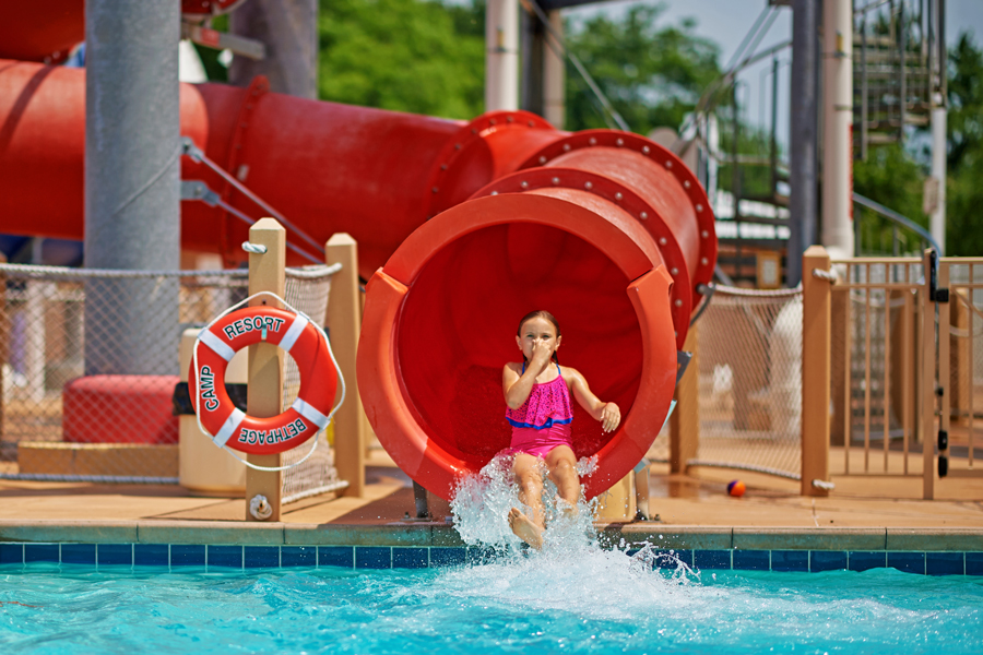A young girl shoots out of a waterslide.