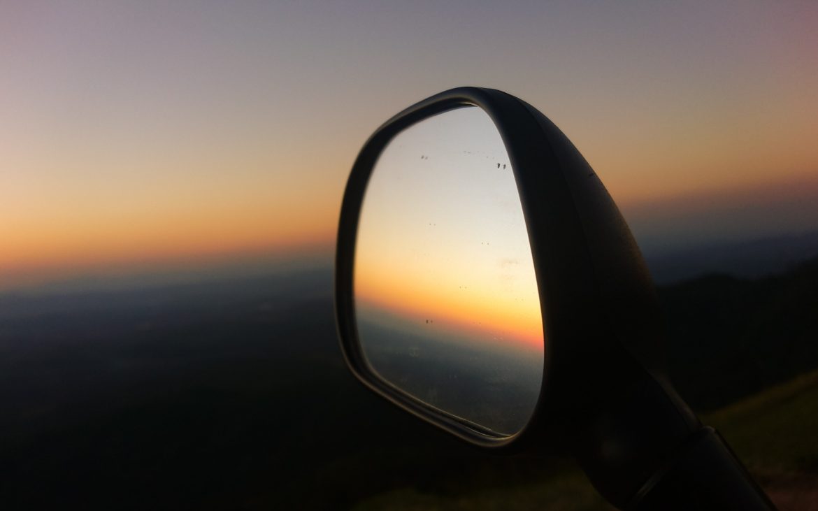 A side mirror reflects a dusk sky.