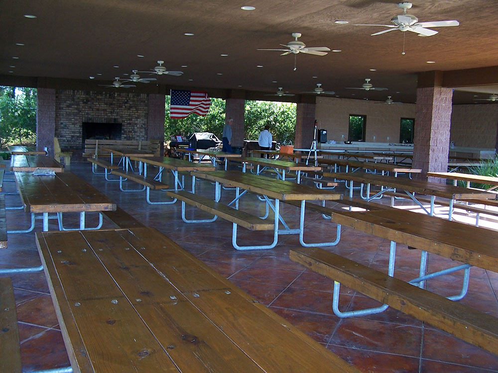 Tables fill a dining hall with a fireplace, red tile floors and ceiling fans