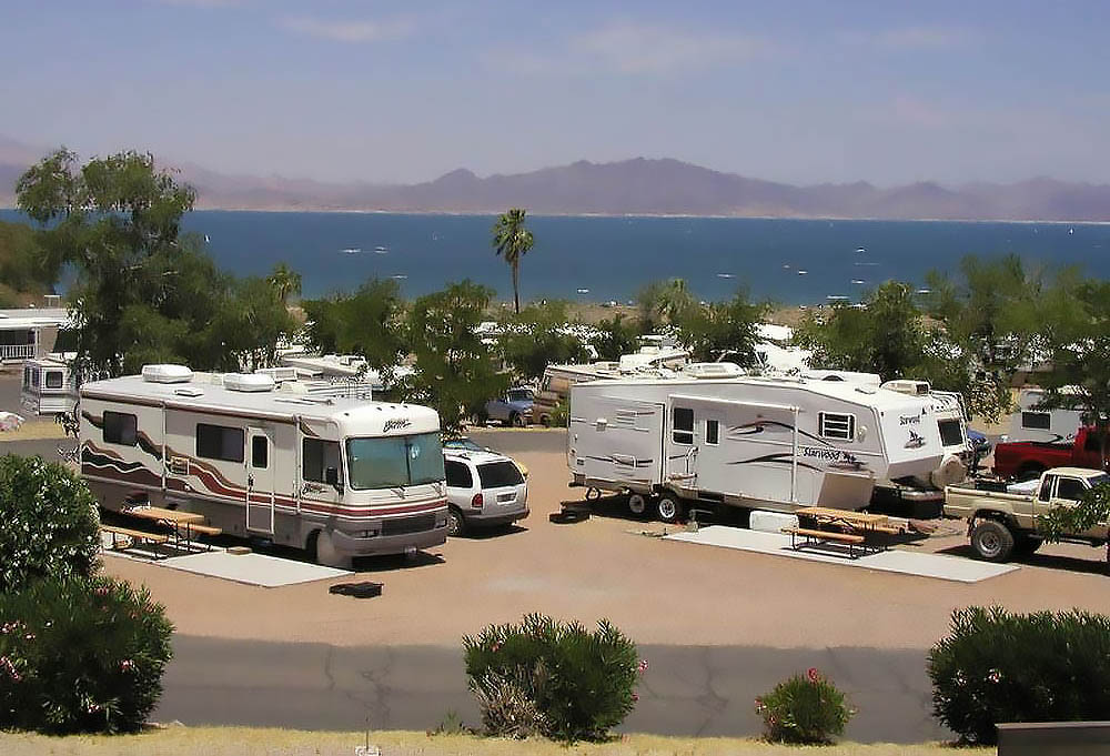 A motorhome and fifth-wheel in the foreground of a lakeside campground on Lake Mead.