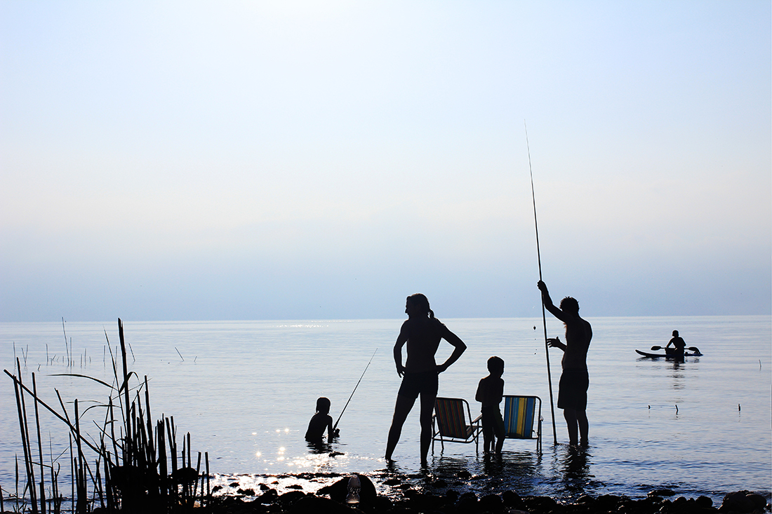A family fishing silhouetted on a lake.