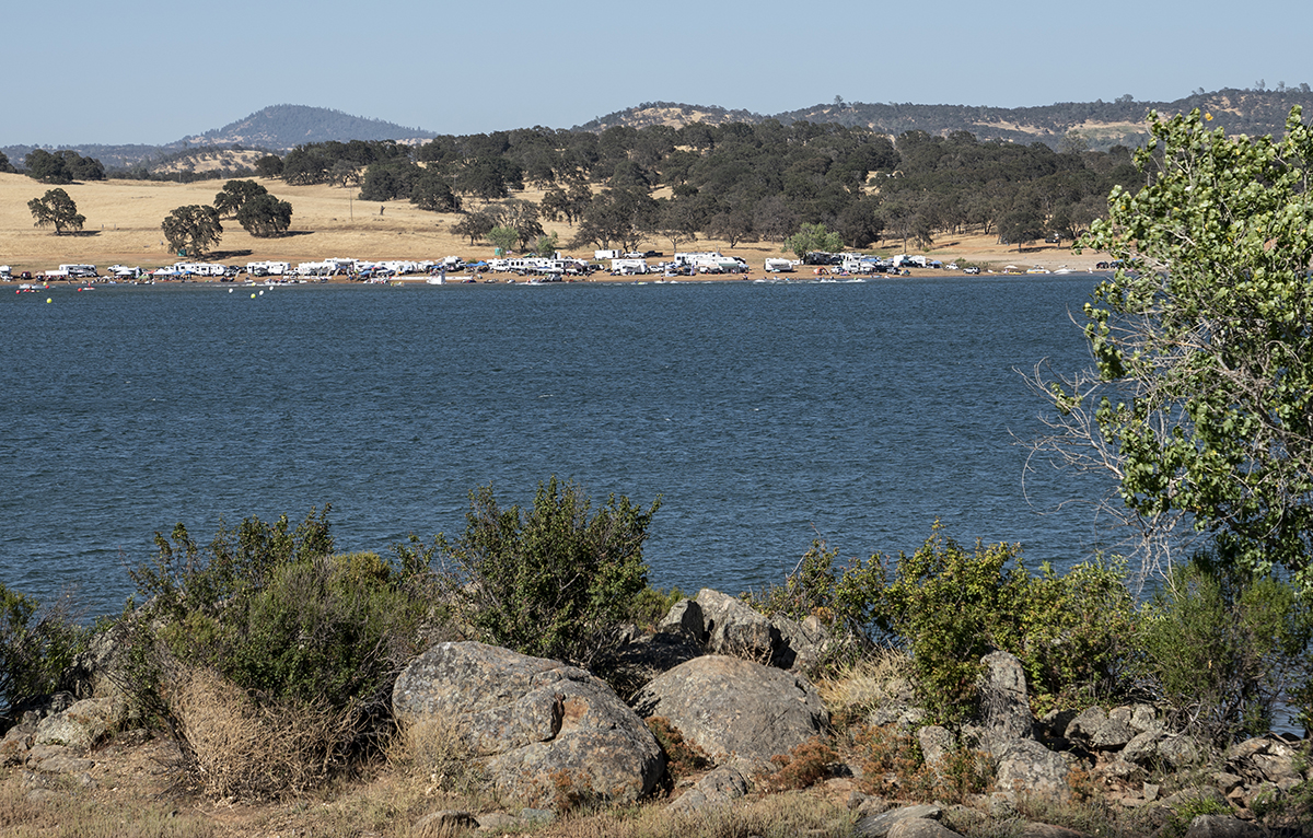 A view from the opposite bank of an RV park nestled on the shores of a lake.