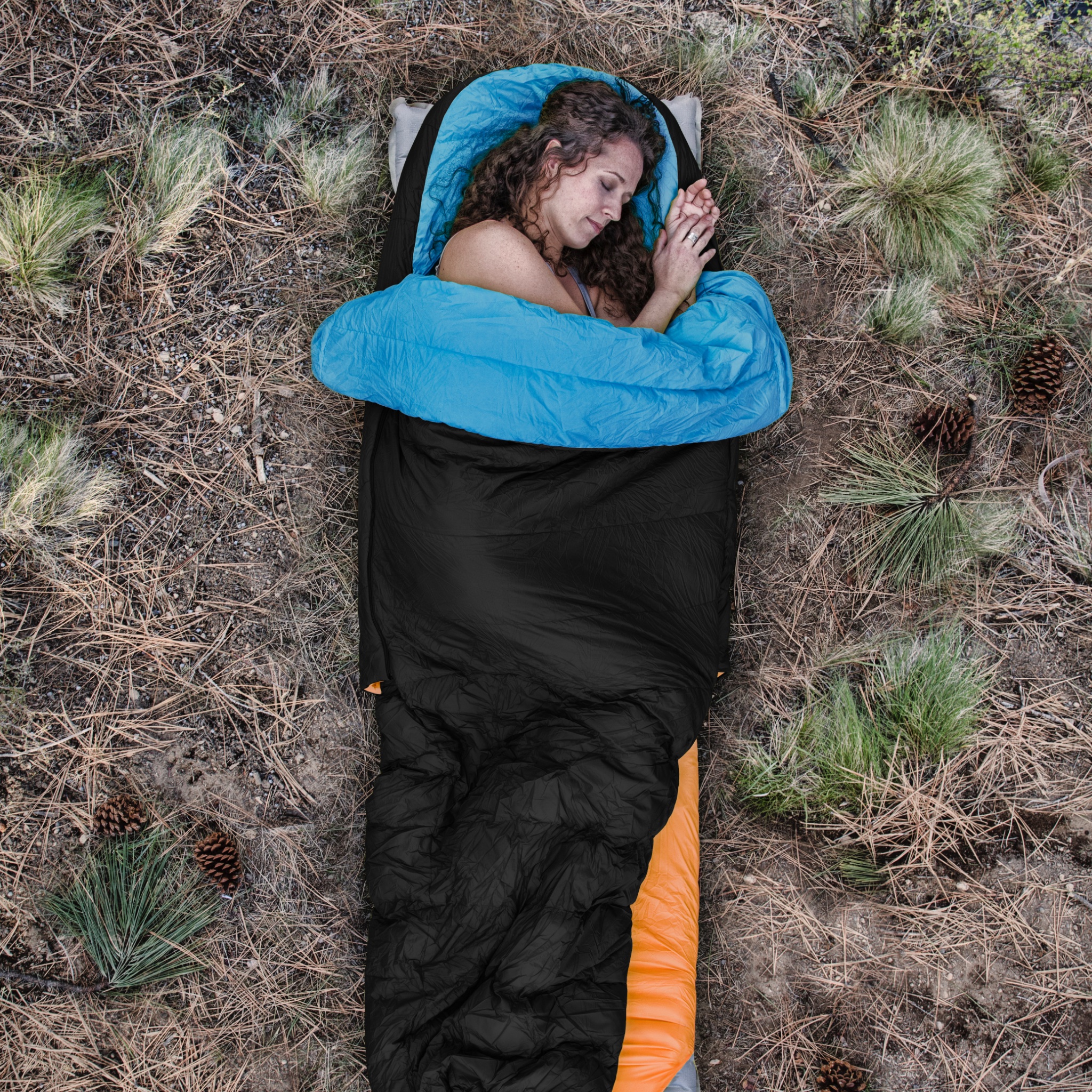 Woman sleeping outside on side in sleeping bag