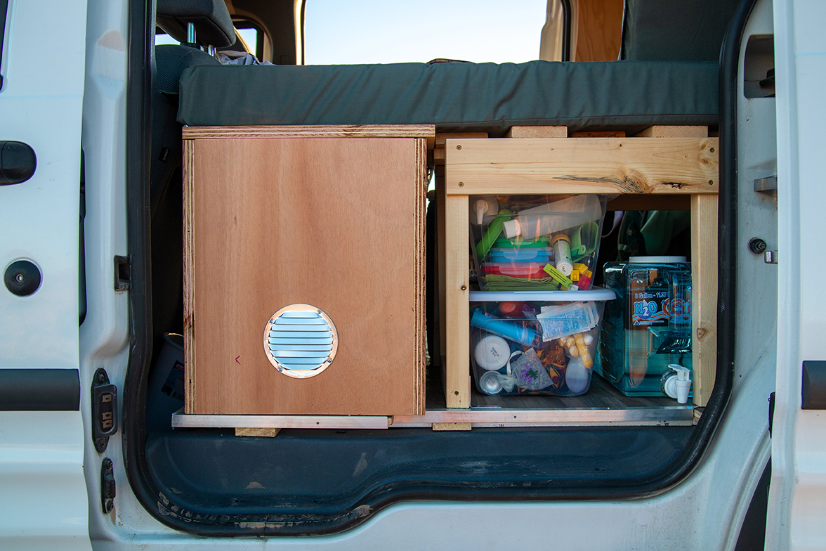 Storage containers — some in clear plastic boxes — inside of a camper van.