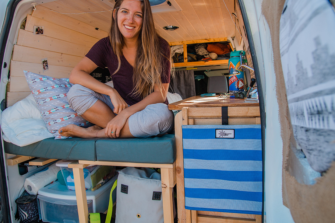 A solo traveler sitting in the back of her camper van.