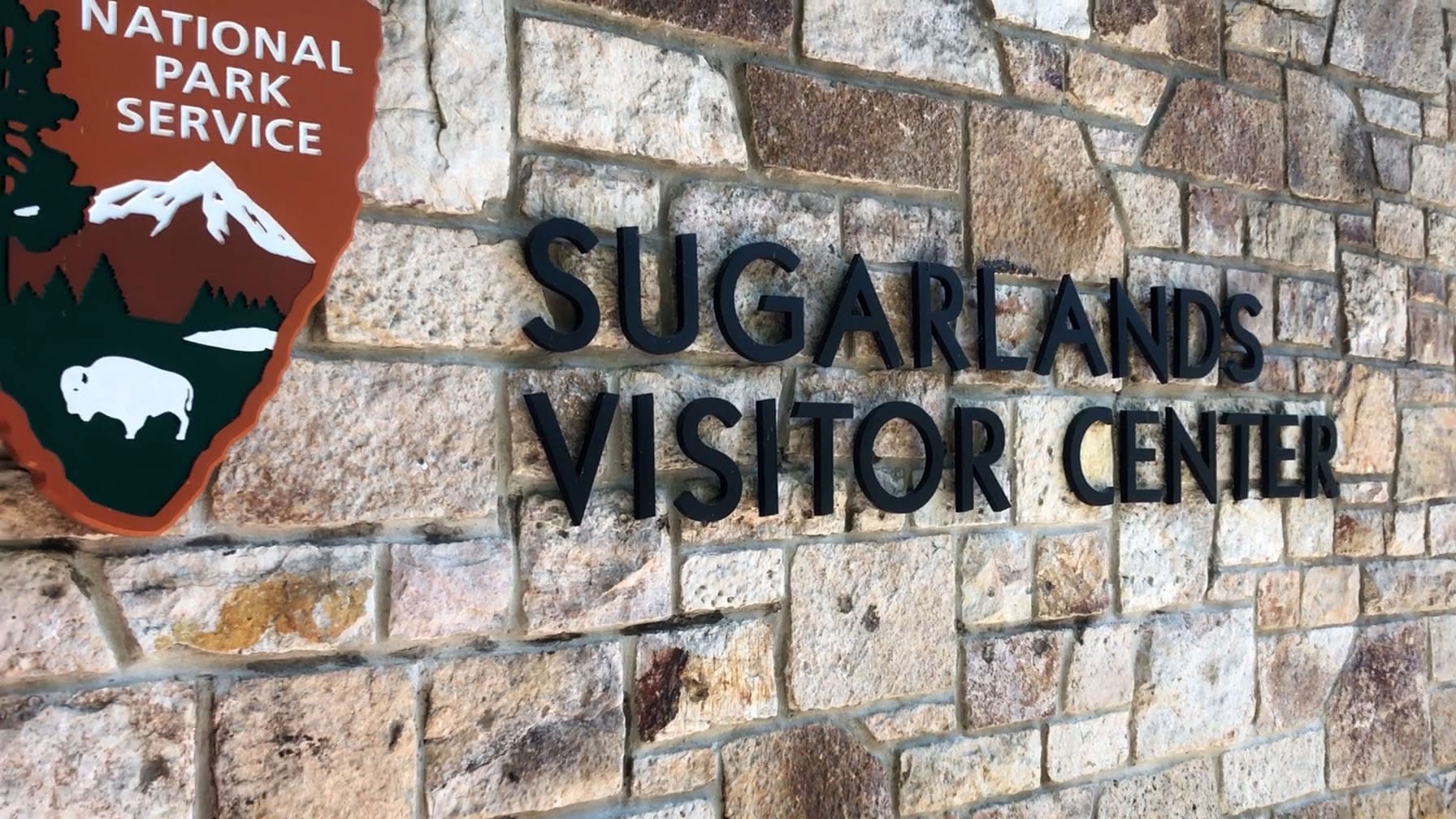 "Sugarlands Visitor Center" sign against a brick wall.