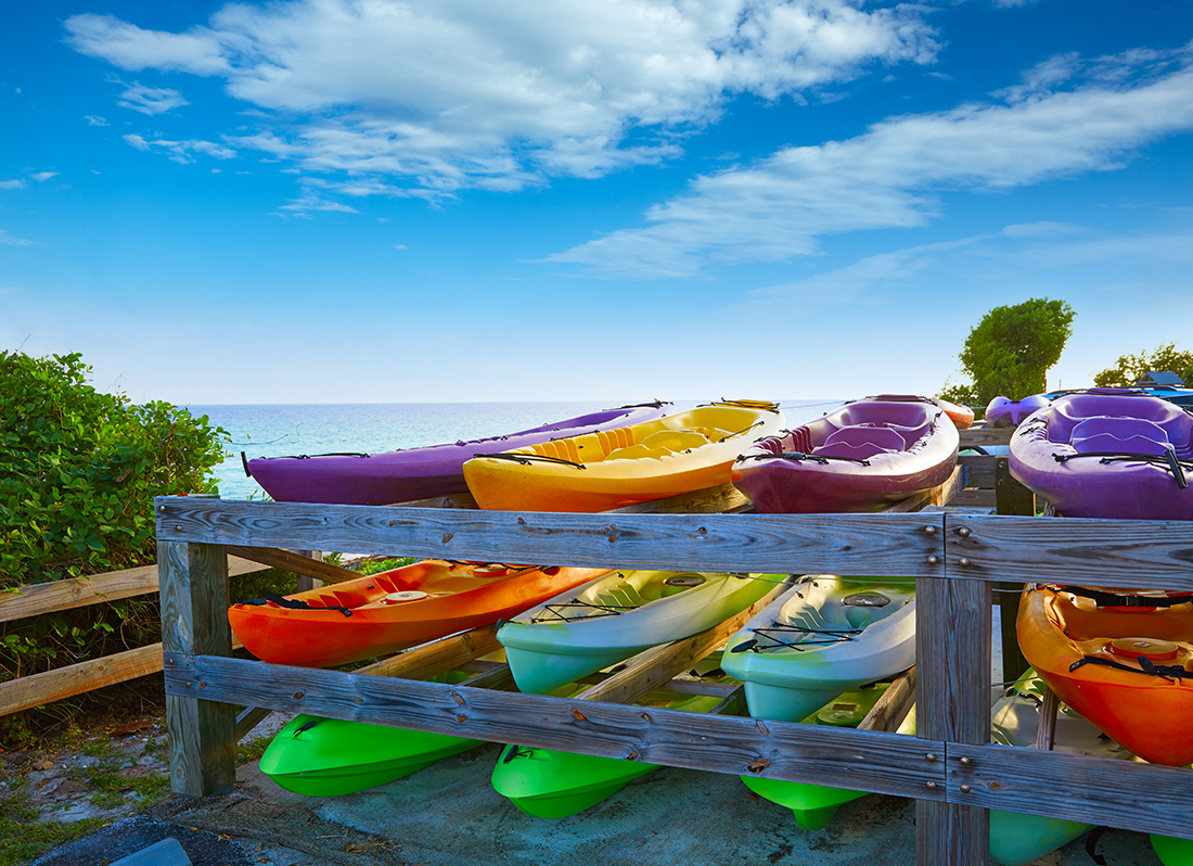 A rack holds three rows of kayaks in purple, lime green, red and yellow hues.