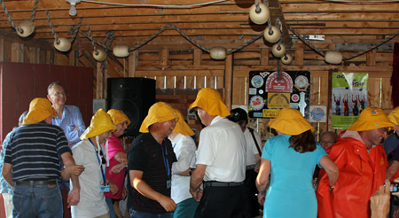 People wearing yellow rain hats dancing inside cabin type building