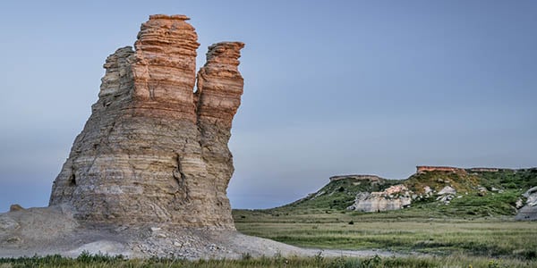 A rock outcropping splits from a solid base into a pair of spire-like formations.