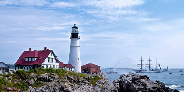 A lighthouse stands on a rock promontory overlooking a the sea.