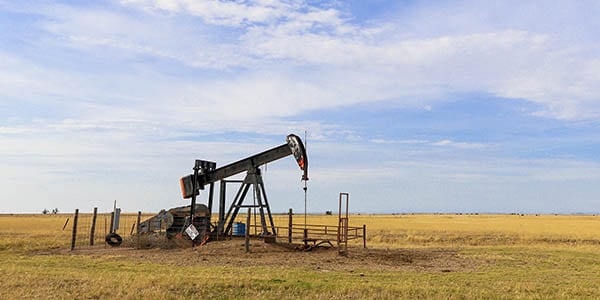 An oil pump in the middle of a green field.