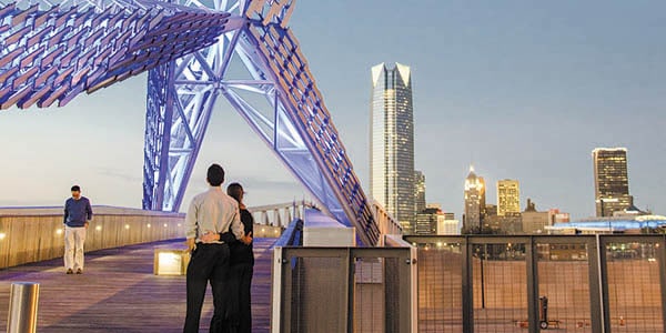 A couple with arms around each other's waists admire a skyline in the distance.