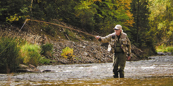 A fly fisherman casts a line down the stream.