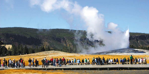 Wyoming outdoor attraction with row of people looking at smoke coming out of mountainside
