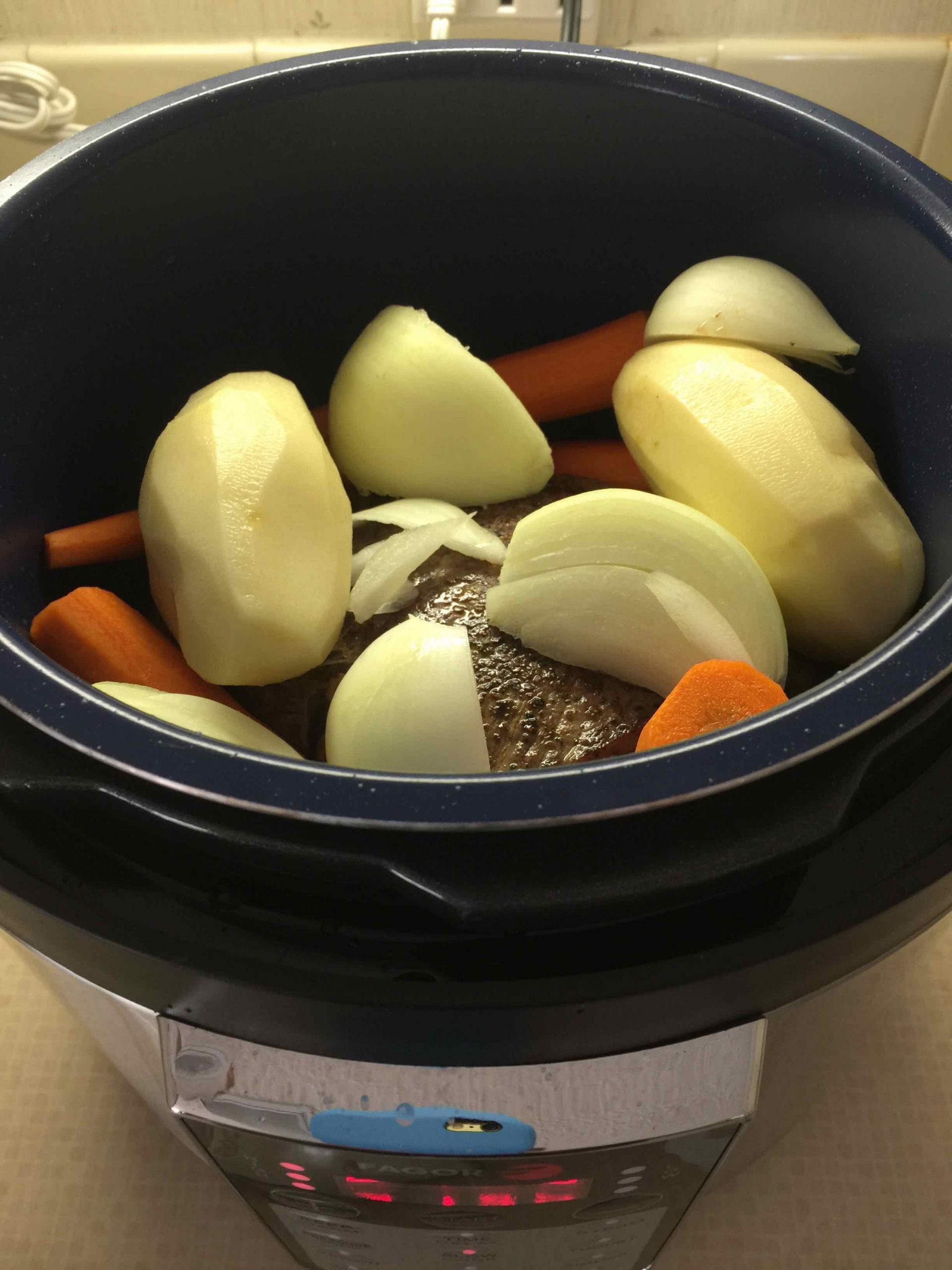 Onions, potatoes and carrots cooking in pressure cooker