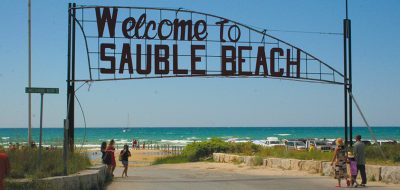 Sauble Beach sign over beach walkway on sunny day