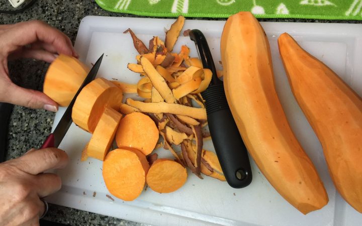 Person cutting and peeling yams on plate