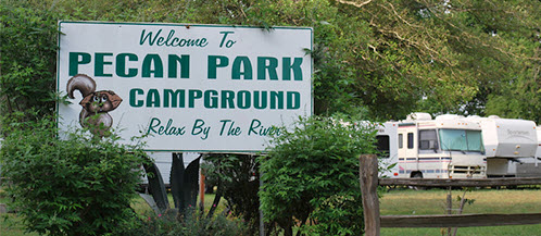 RVs camped amid trees at Pecan Park Riverside RV, San Marcos, TX