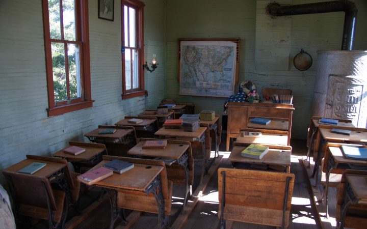 Old classroom with wooden desks and books on top