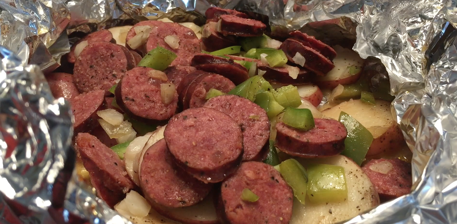 Red potatoes, green peppers, onion, sausage, butter, pepper and salt in tinfoil