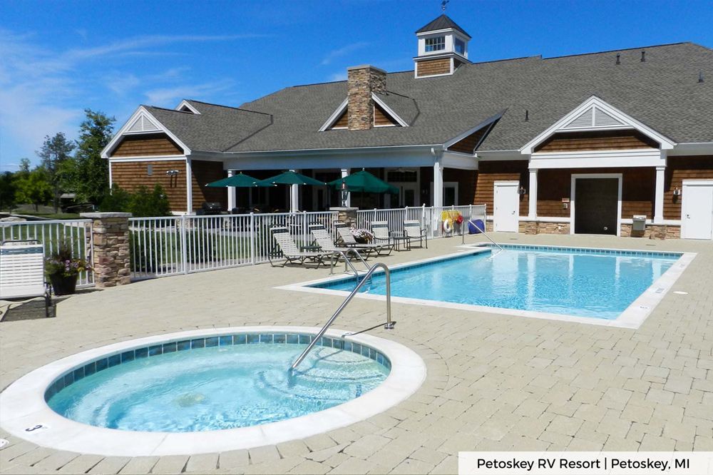 Outdoor pool with circle spa within white gate at Petoskey RV Resort