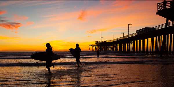 Couple with surf boards at sunset.