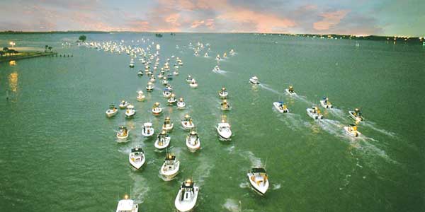 A fleet of fishing boats head out to sea.