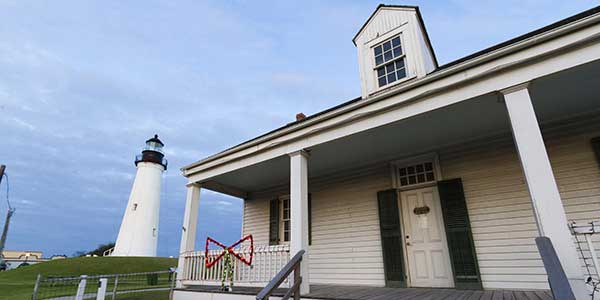 A lighthouse and clapboard house. 
