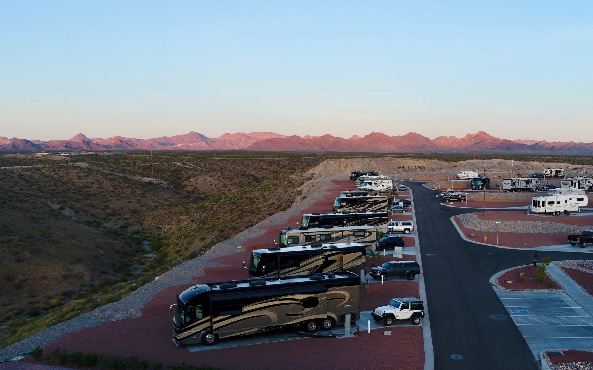 Drone shot of RVs parked in a row in a desert RV park.
