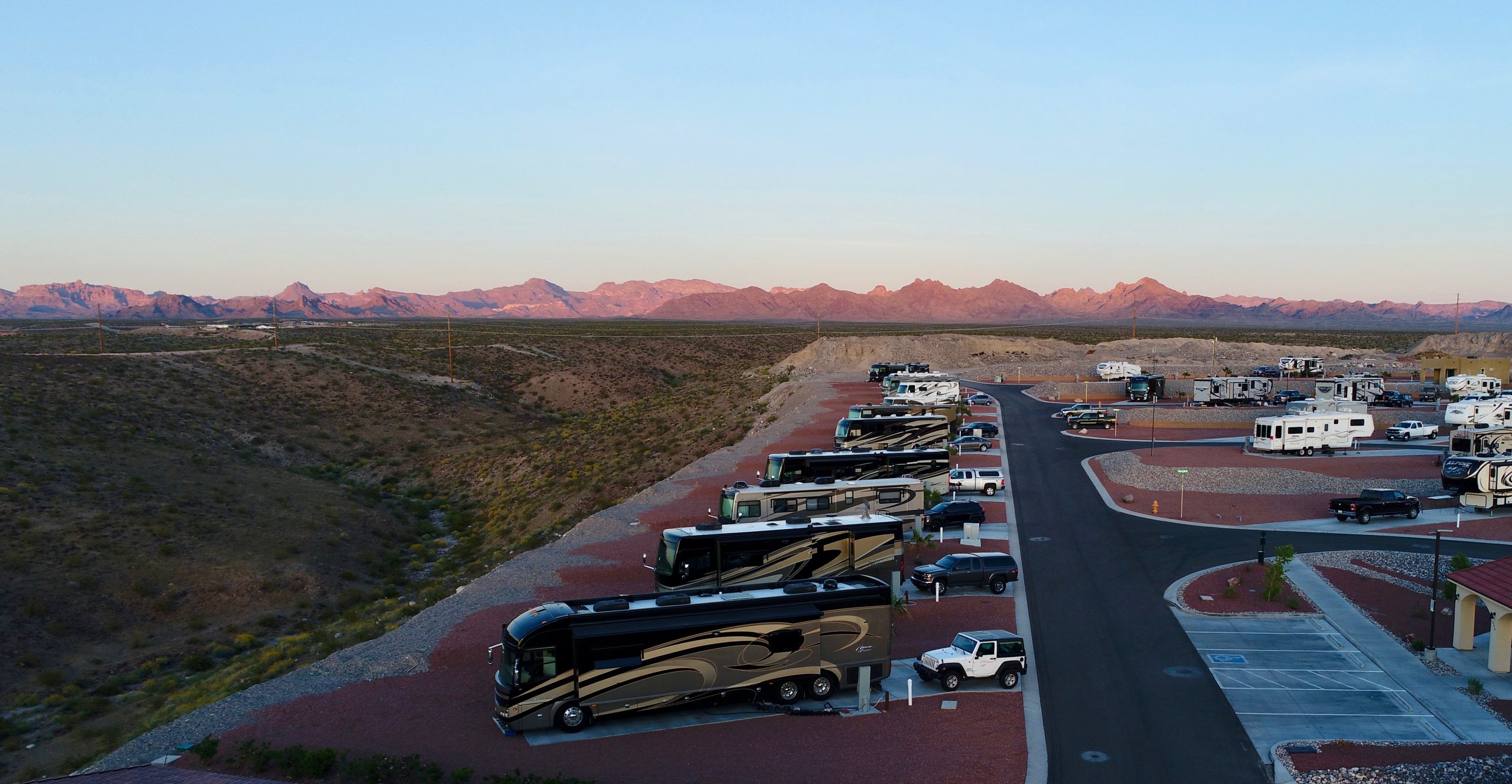 Drone shot of RVs parked in a row in a desert RV park.