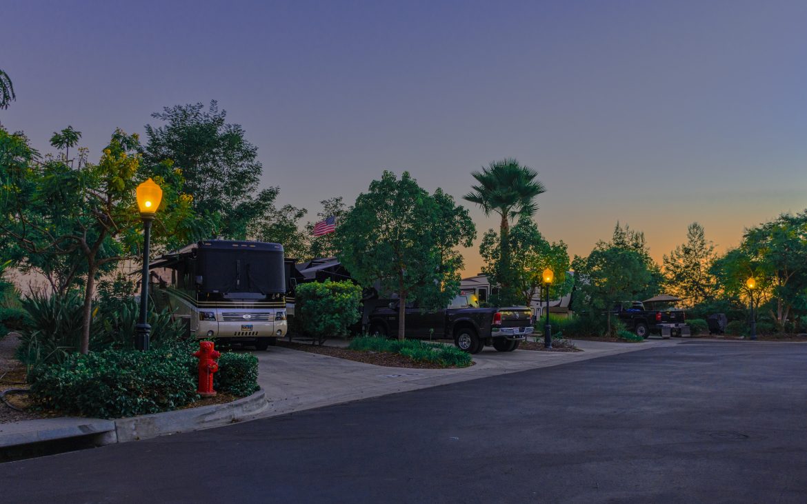 Large motorhome parked in driveway with green trees at dusk