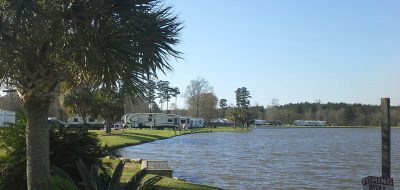 Natalbany Creek RV Park and Campground lake with RVs on sunny day