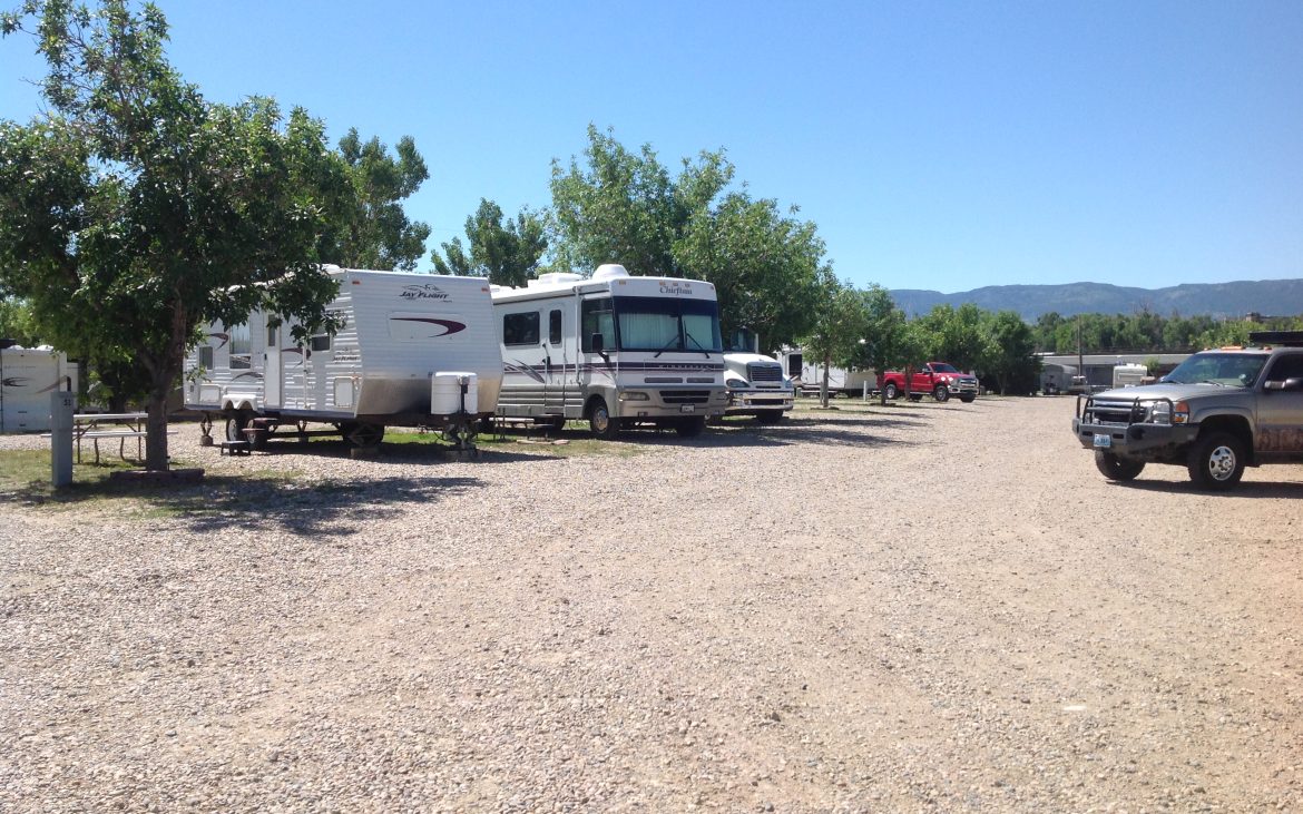 White motorhome and travel trailer parked along dirt RV area