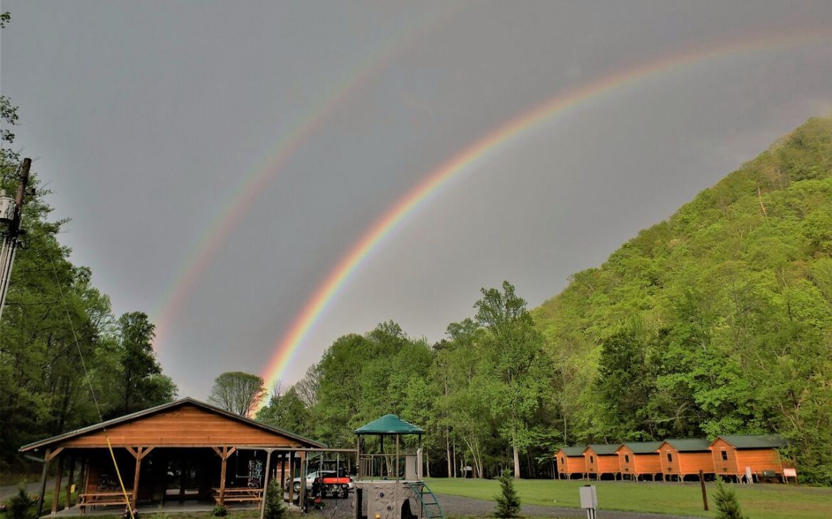Rainbow overlooking campground on grey sky day