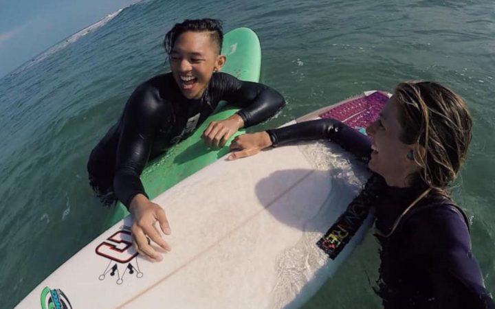 Boy surfing in the ocean with a woman