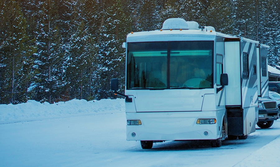 Winter Rving. Class A Recreation Vehicle on the Park Parking Covered by Snow. Winter Boondocking.