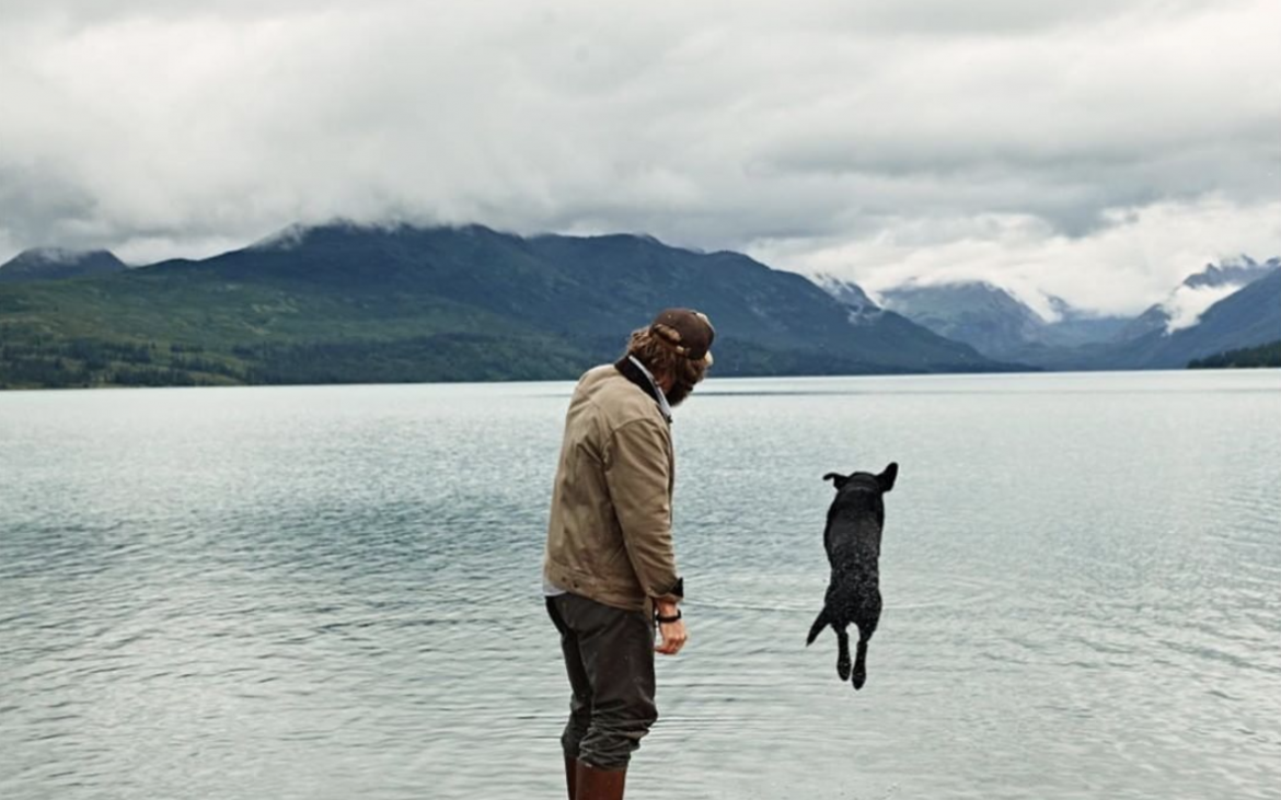 Man looking at dog jumping in lake
