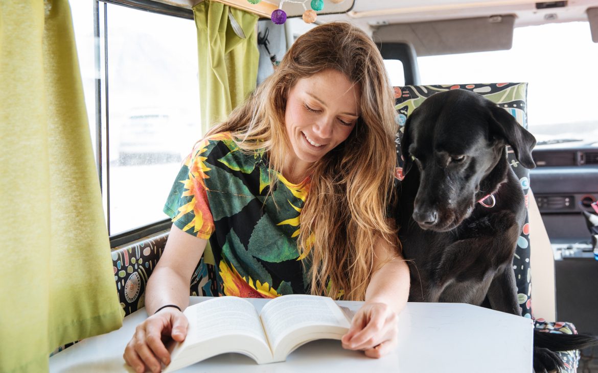 woman and dog reading in camper van
