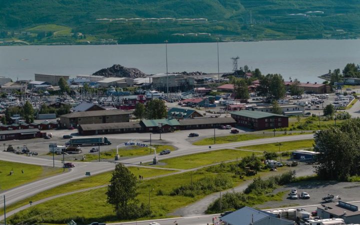 Daytime aerial view of RV's parked with the Prince William Channel and snowy mountains in the distance.