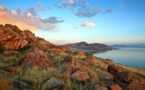 Beautiful red rock and grass hill overlooking the ocean at sunset.