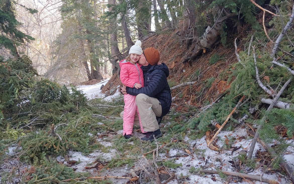 Father kissing daughter in the snow of Angeles Crest