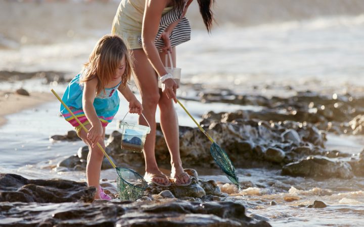 Mother and daughter spend the day fishing at the beach together having fun and bonding over some quality parent childhood time