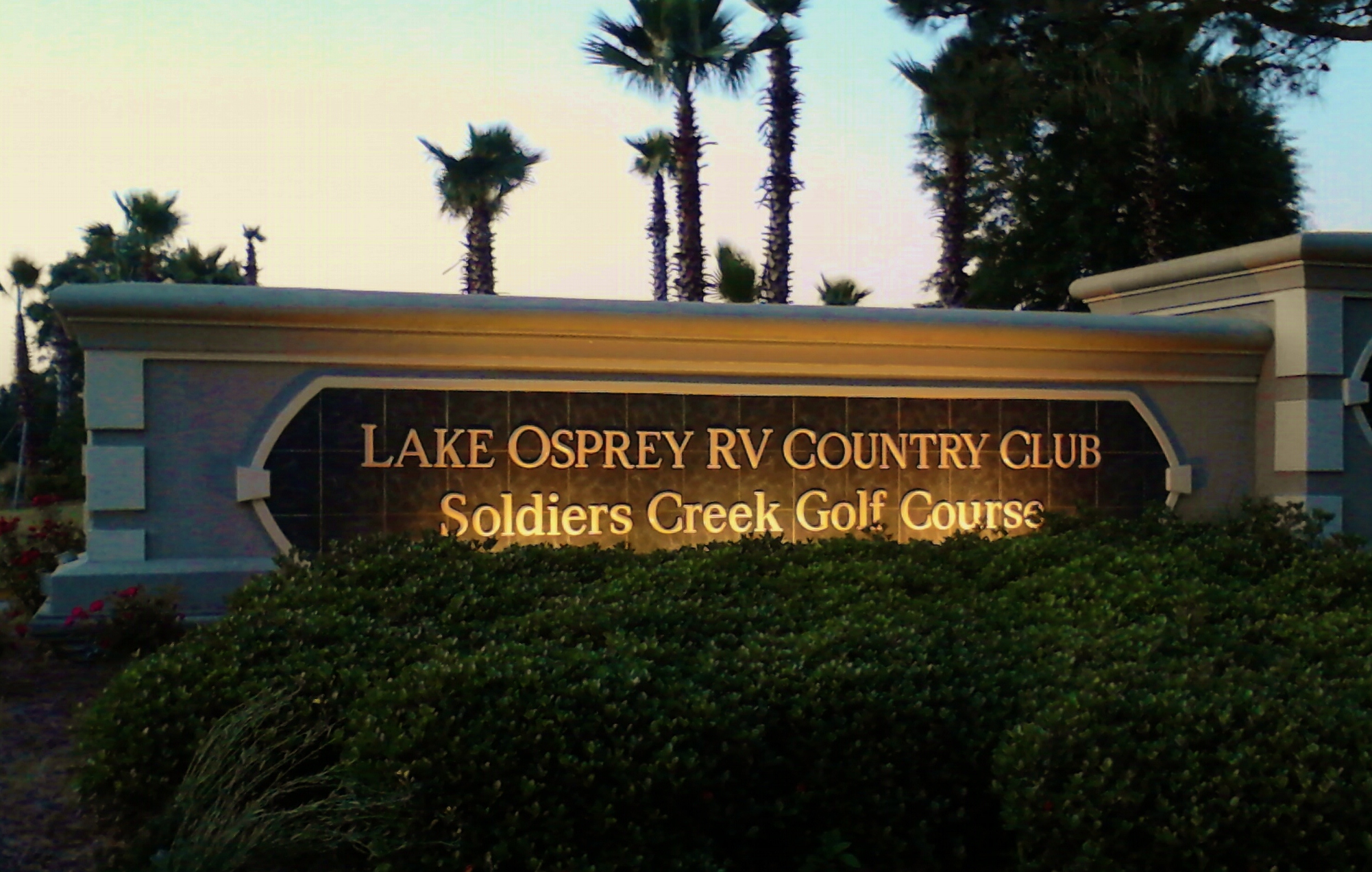 Entry sign to Lake Osprey RV Resort lit at dusk