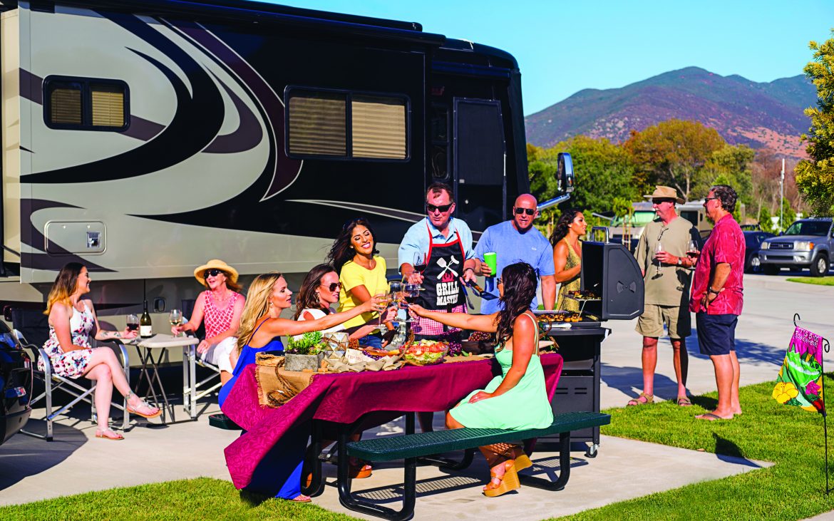 large family and friends enjoying a picnic next to a large RV