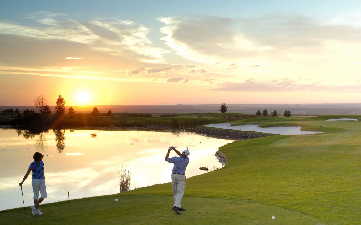 Man golfing at sunset on green golf course