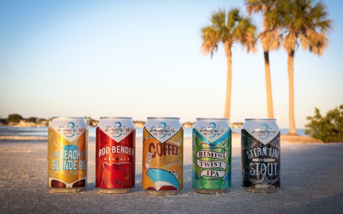 beer cans on the sand with palm trees in background