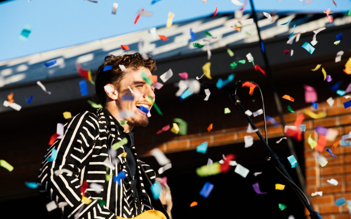 Performer in black and white jacket on stage with confetti flowing
