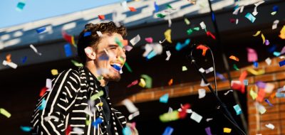 Performer in black and white jacket on stage with confetti flowing
